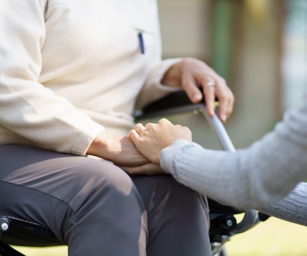 Family relationship Asian senior woman in wheelchair with happy daughter holding caregiver for a hand while spending time together.